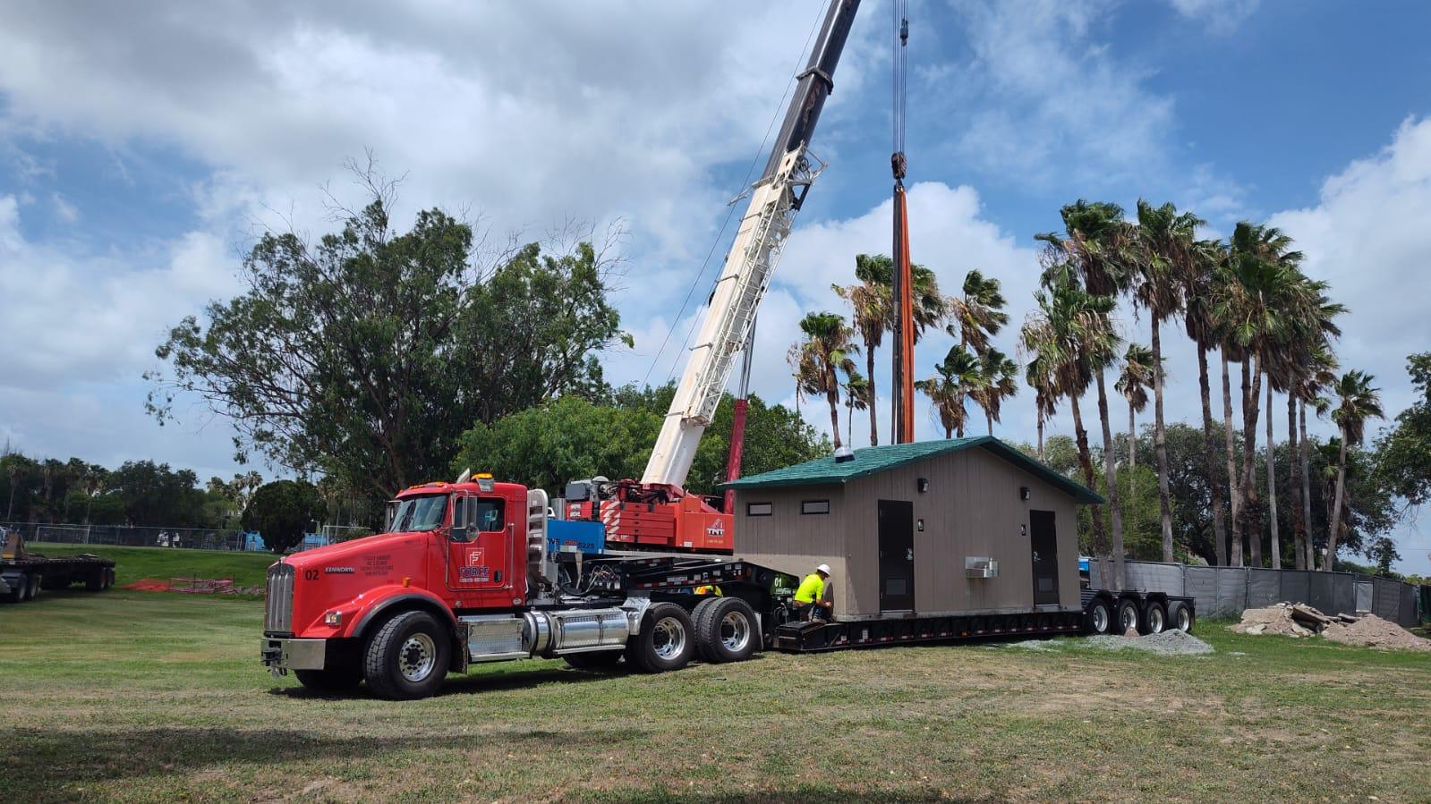 Crane lifting building onto lowboy