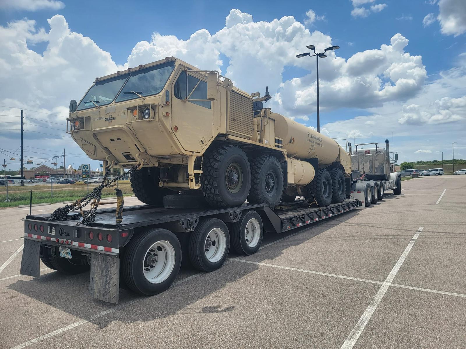 Oshkosh 8x8 tanker truck chained down on a step deck trailer